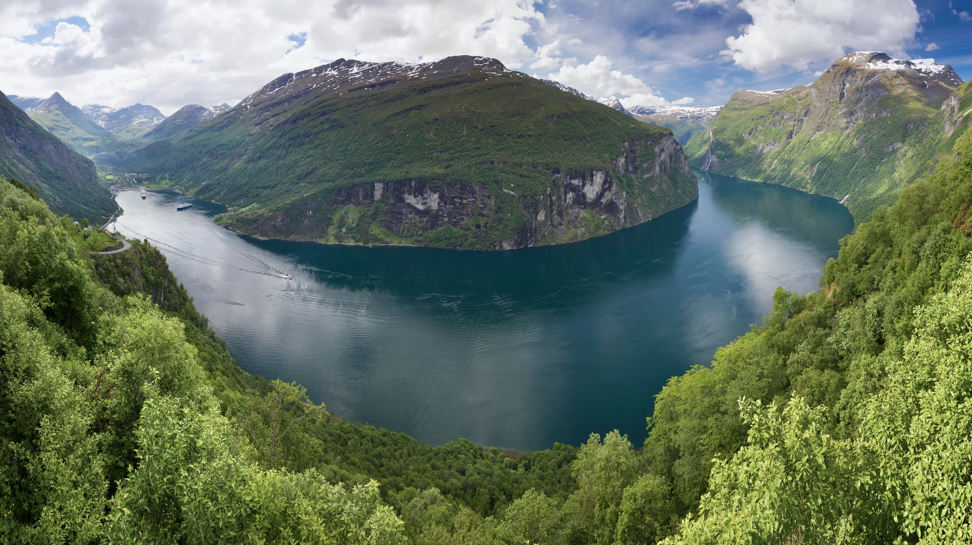 Geirangerfjord visto do mirante Ørnesvingen, com o fiorde serpenteando entre encostas verdes.